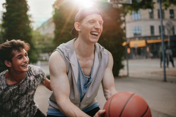 Man laughing while playing basketball