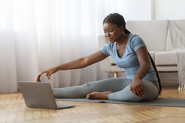 A woman stretching indoors in front of a computer