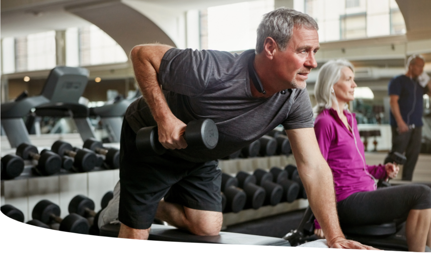 Senior man and woman strength training with weights at the gym